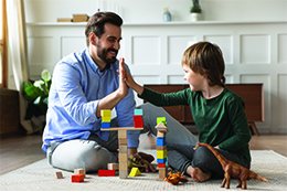 Male counsellor high fiving young boy playing with blocks
