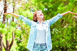 Young woman outdoors with arms in the air.